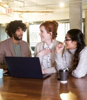 people talking around a laptop