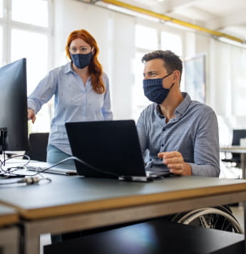 man and woman at computers wearing face masks