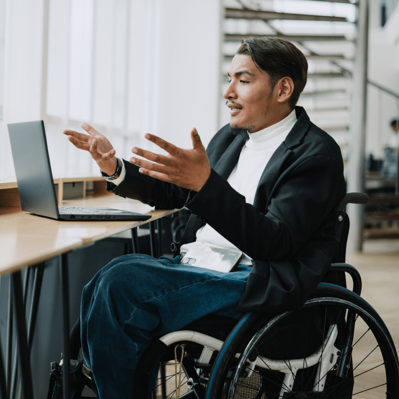 A man in a wheelchair talking to someone on a computer